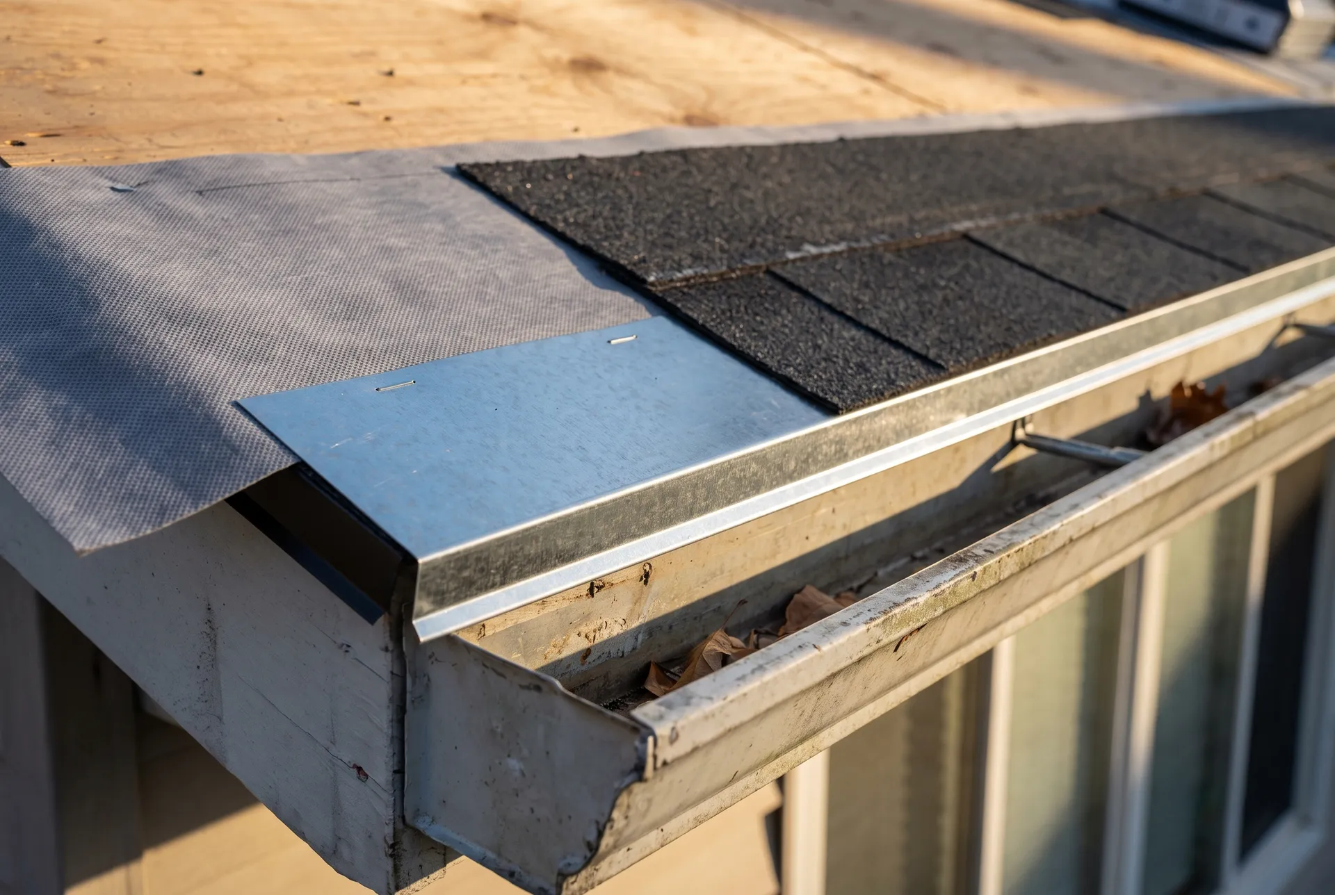 A roof eave showing new drip edge, underlayment and the first course of shingles